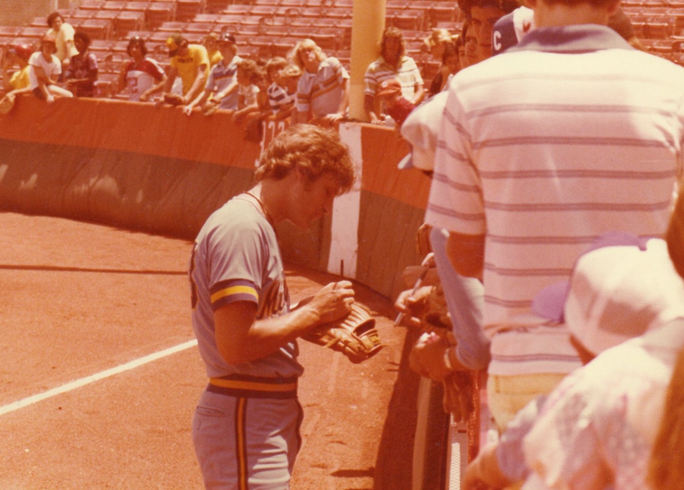 Randy signing an autograph for fans beside the field