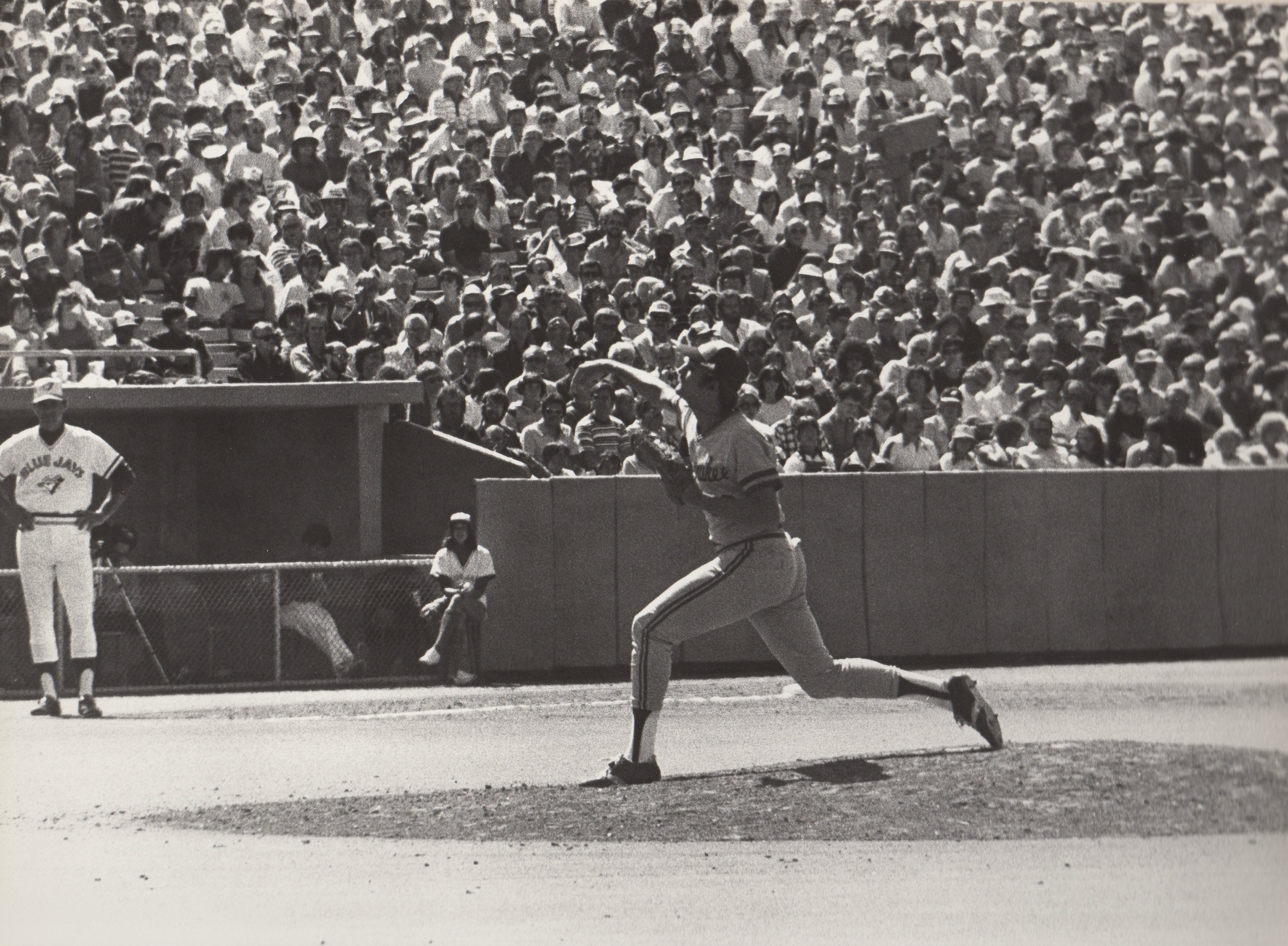 Black-and-white photograph of Randy delivering a pitch in front of a crowded grandstand